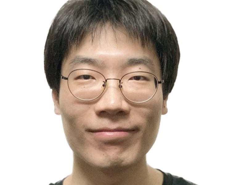 Early career man with glasses and short black hair wearing a black t-shirt