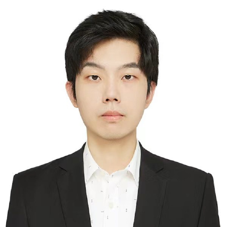 A man with short dark hair wearing a black blazer and white shirt, photographed against a plain light background.