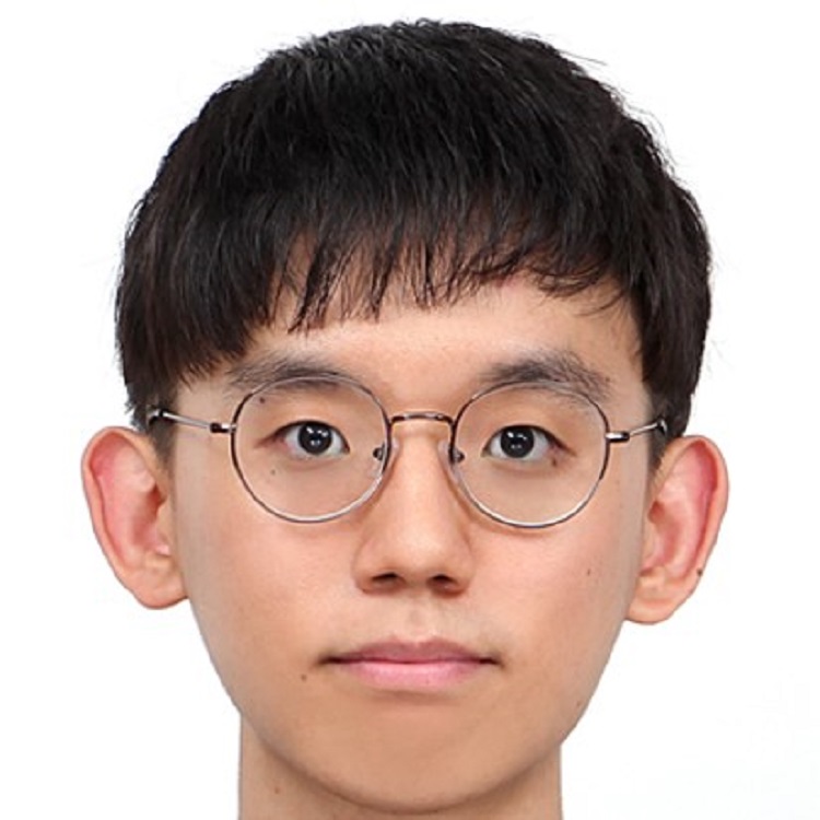 A man with short dark hair wearing round wire-framed glasses, photographed against a plain light background.