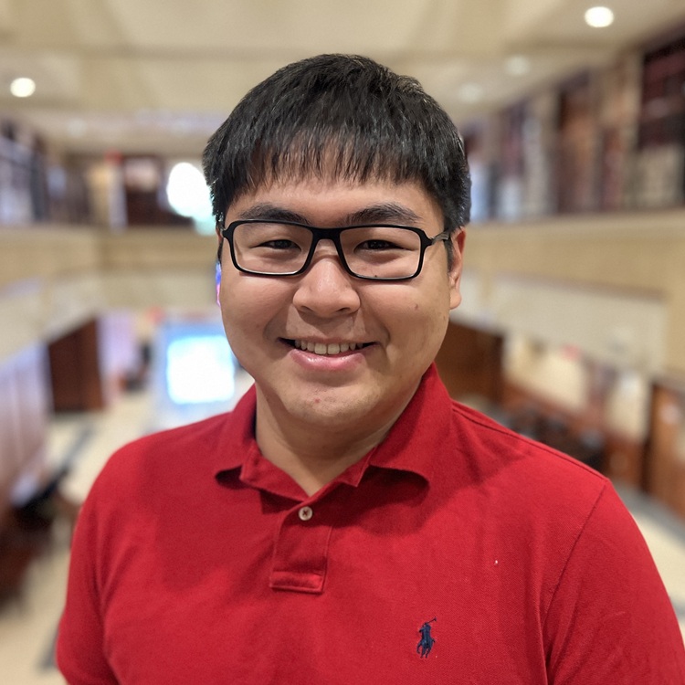 Man with glasses and a red shirt smiling with a blurred background